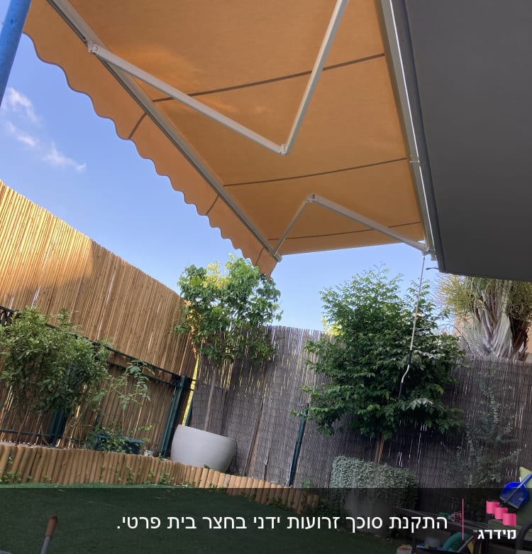 סוכך כתום עם זרועות מתכת לבנות בגינה
